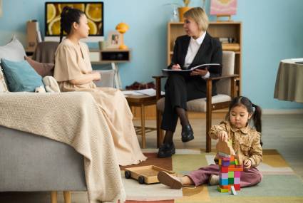 Counseling session taking place with therapist and female client discussing important matters while child plays with building blocks on floor