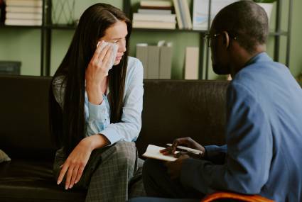 Counselor offering support to distressed woman by providing guidance and understanding in office setting helping cope with emotions and challenges