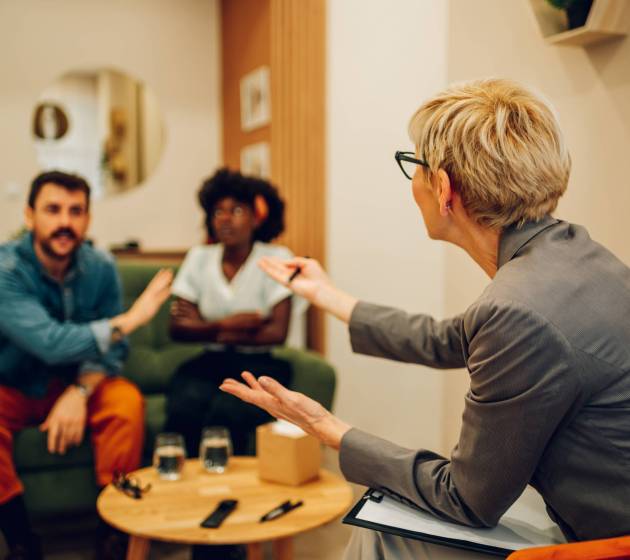 Multiracial boyfriend and girlfriend or spouses meeting therapist or counseling psychologist in an office. Focus on a rear view of a couple therapist. Copy space.