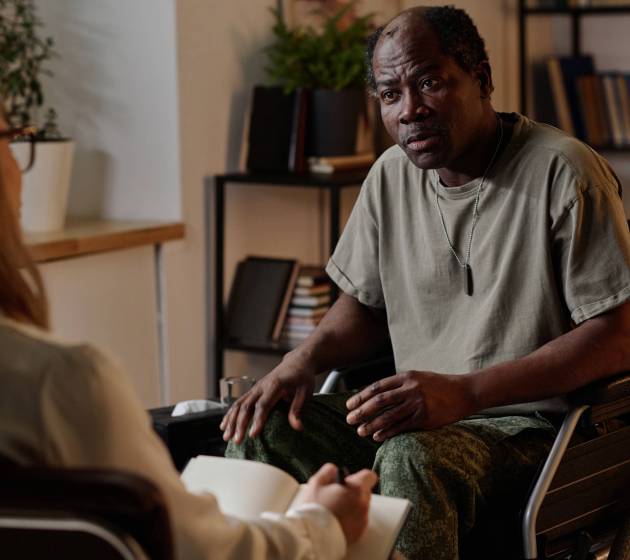 War veteran with disability attentively listening to his female therapist during individual session