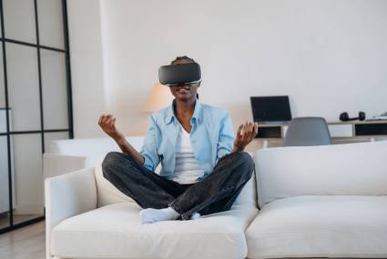 On the sofa in virtual reality headset. Woman is at home in domestic room.