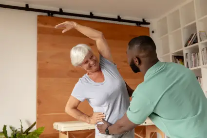 smiling-senior-woman-stretching-with-physical-ther-2026-03-25-06-33-28-utc
