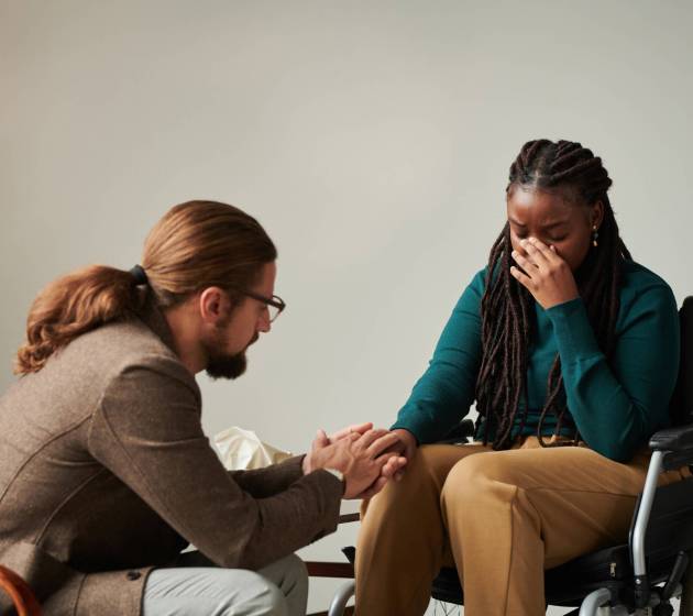 Psychotherapist holding hand with patient with disability and supporting her during rehabilitation