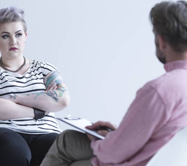 Troubled girl with tattoo and dark makeup talking with psychologist