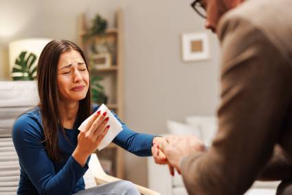 Young woman cries during therapy with a psychologist